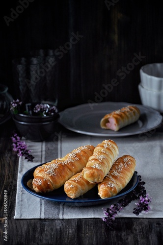 On a wooden table on a plate a bunch of sausages in a dough