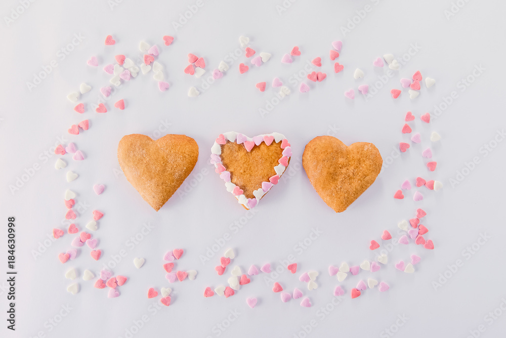 Homemade cookies in the form of hearts in the frame of sugar candy hearts decor on the white background. Valentine day concept. Gift for lover. Selective focus. Space for text.