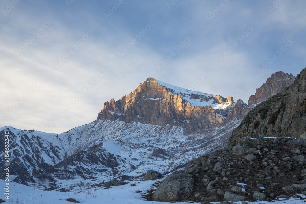 Горный пейзаж. Высокие скалы в живописном ущелье, зима, белые облака на синем небе. Дикая природа Северного Кавказа