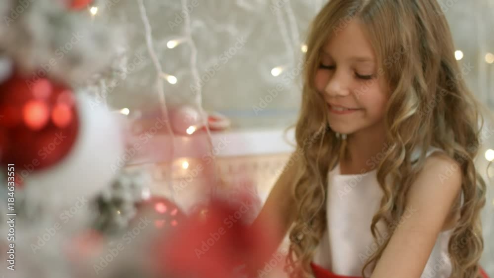 Beautiful girl with long hair in the dress decorates Christmas tree Beautiful girl with long hair in the dress decorates Christmas tree