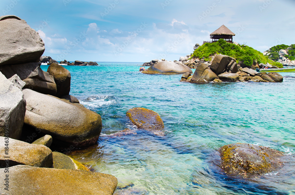 Beautiful outdoor view of white sand, blue water, many rocks in the water and gorgeous sky at Cabo San Juan, Tayrona Natural National Park, Colombia