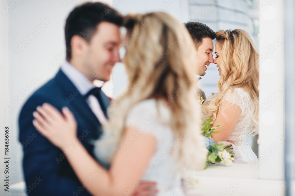 A pair of lovers of happy newlyweds is reflected in a mirror. Bright white studio. A pair of lovers of happy newlyweds is reflected in a mirror. Bright white studio.
