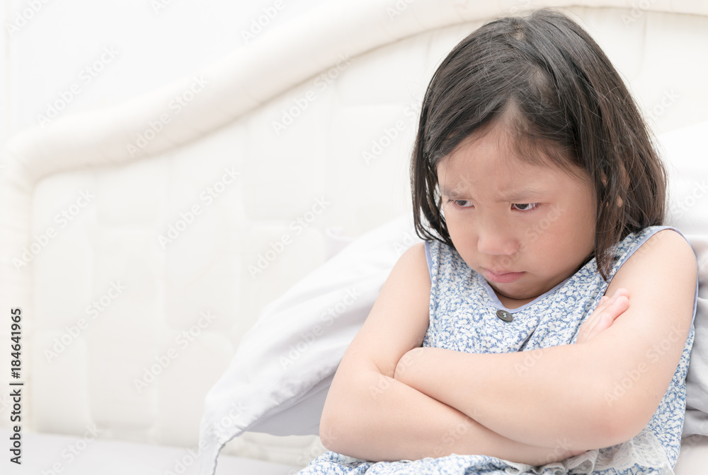 Angry and sad little girl sitting on the bed Angry and sad little girl sitting on the bed