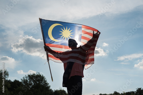 Silhouette of a boy holding malaysia flag