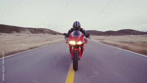 Motorcyclist racing his motorcycle down straight country road going a high speed  at sunset