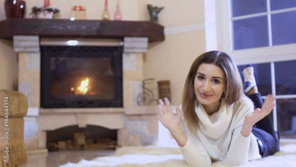 Young charming girl send air kiss to camera laying near fireplace Young charming girl send air kiss to camera laying near fireplace