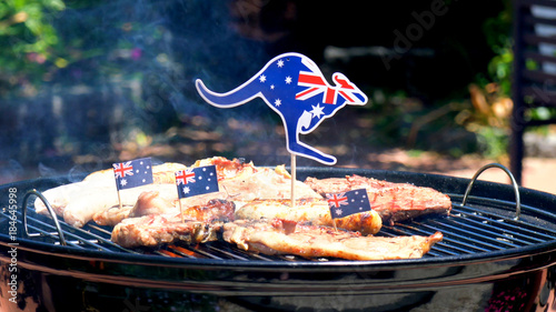 Iconic Australian BBQ close up of man cooking chops, sausgaes and steak, outdoors in garden setting. 