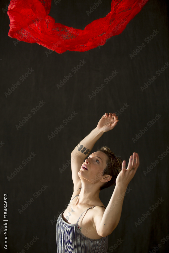 Young woman in silver dress with red scarf floating above. Young woman in silver dress with red scarf floating above.