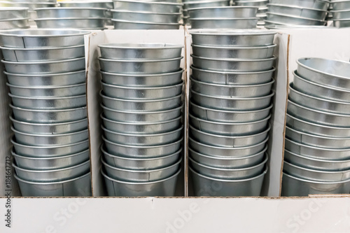 Stacks of silver tin buckets in white corrugated boxes.