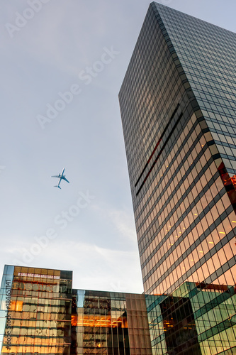 view from below upwards on glass modern skyscrapers and flying airplane