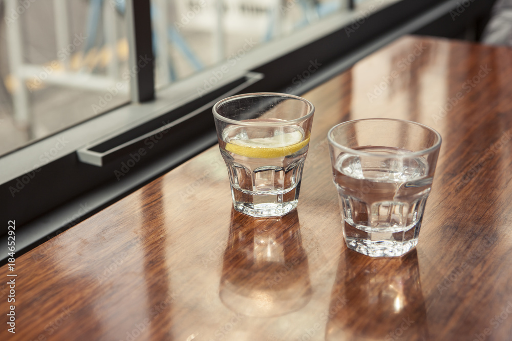 water and lemon with cup(glass) on the wood table.