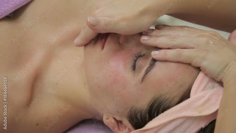 Close-up on female face of hands make rejuvenating massage. Master moves his fingers over facial skin of patient whose eyes are closed. Close-up on female face of hands make rejuvenating massage. Master moves his fingers over facial skin of patient whose eyes are closed.