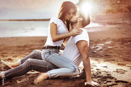 Fashion shot of an attractive couple kissing on a beach photo