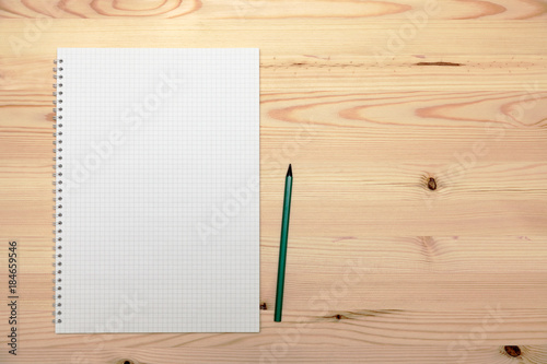 Notepad (copybook) with spiral and pencil on light wooden table, top view