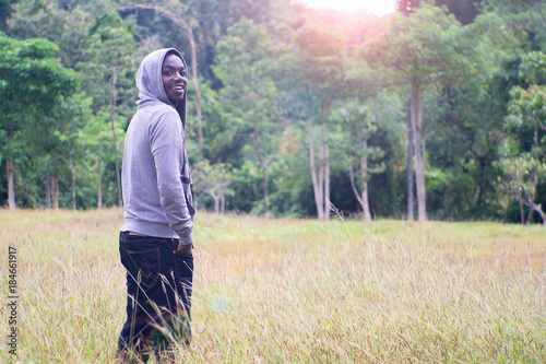 Freedom African Man standing with smile and happy at meadow and green forest with light flare. © arrowsmith2