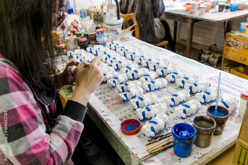 girl paints Christmas toys at a factory of Christmas toys