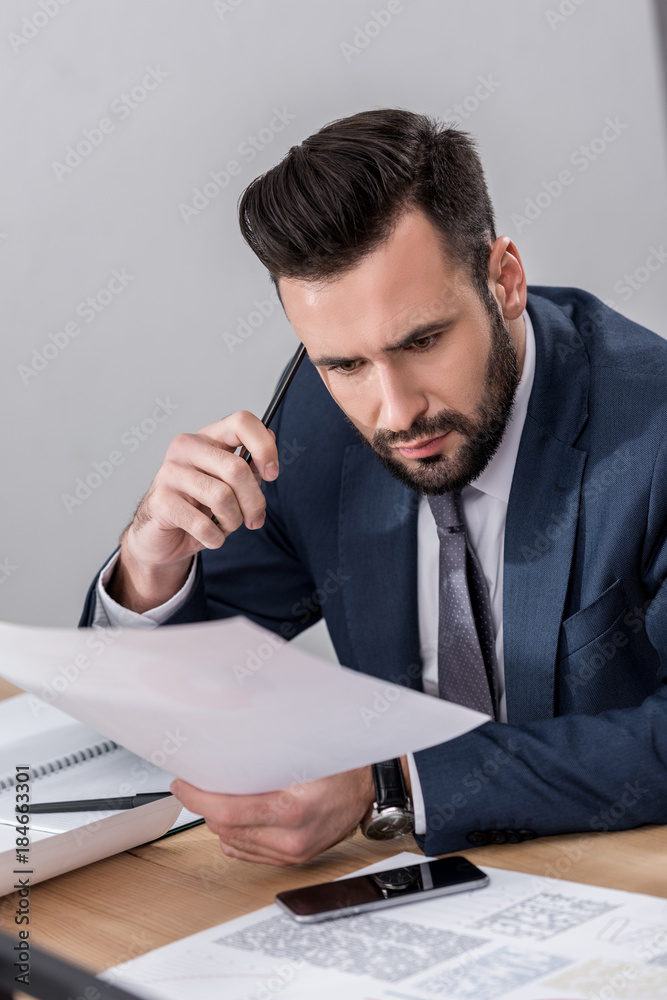 businessman sitting at table and looking at documents with surprise businessman sitting at table and looking at documents with surprise