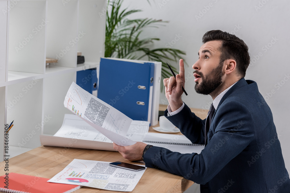 Naklejka premium businessman sitting at table and showing idea gesture