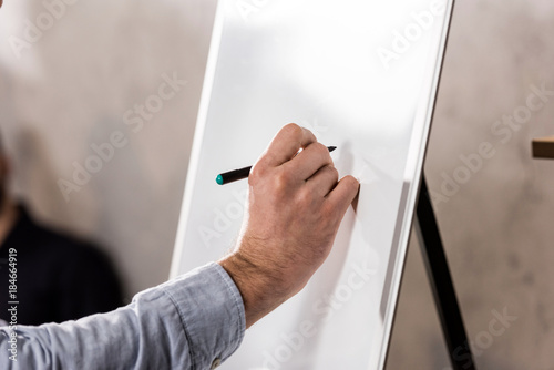 cropped image of businessman writing something on flipchart