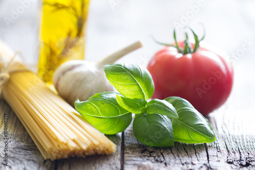 Basil tomato and garlic italian food still life with pasta on retro planks
