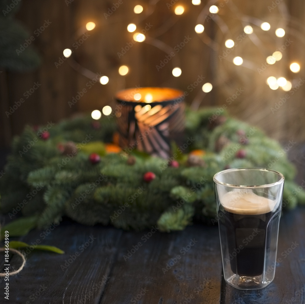 Coffee in a glass on a table and glowing Christmas tree on a dark background