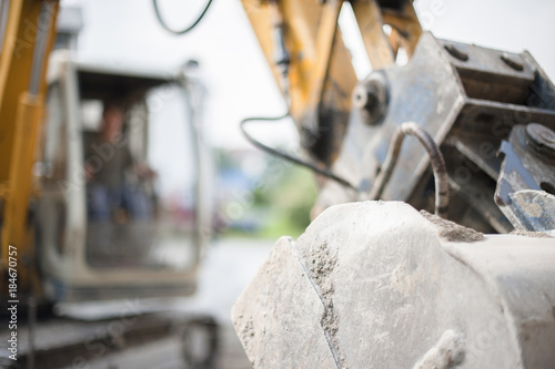 Baggerschaufel mit Bagger im Hintergrund