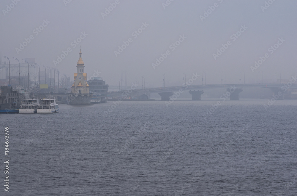 Foggy morning cityscape. View to the embankment near the river port. Kyiv, Ukraine