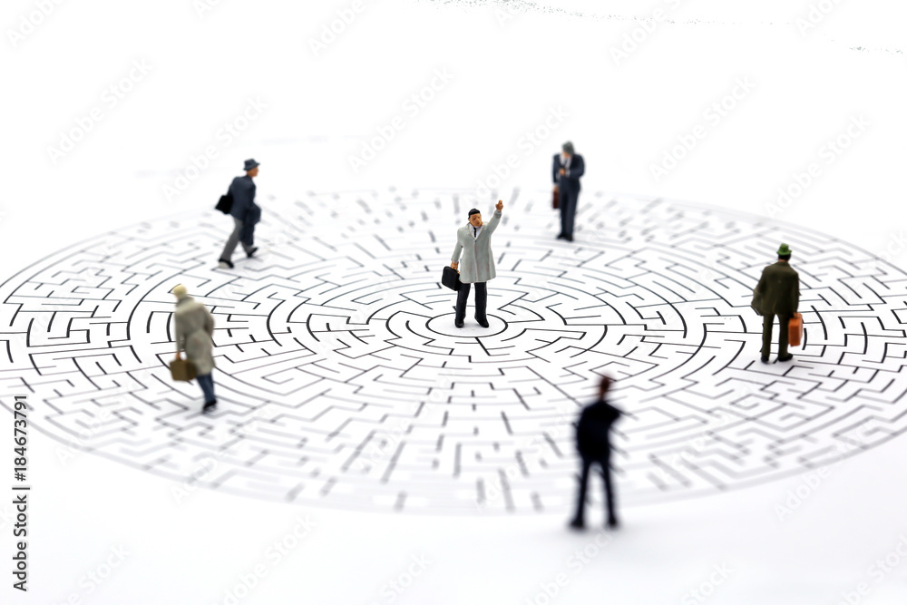 Miniature people: Businessman teams standing on center of maze Miniature people: Businessman teams standing on center of maze