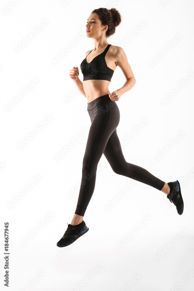 Full length image of Smiling fitness woman running in studio