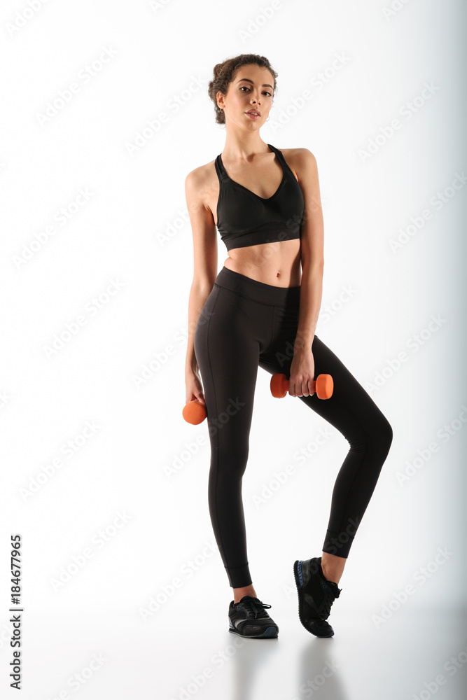 Full length image of beauty fitness woman posing with dumbbells