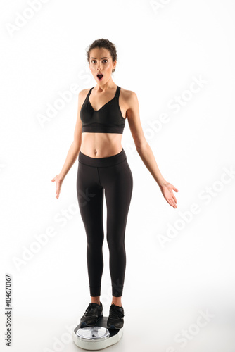 Full length image of Shocked curly brunette fitness woman
