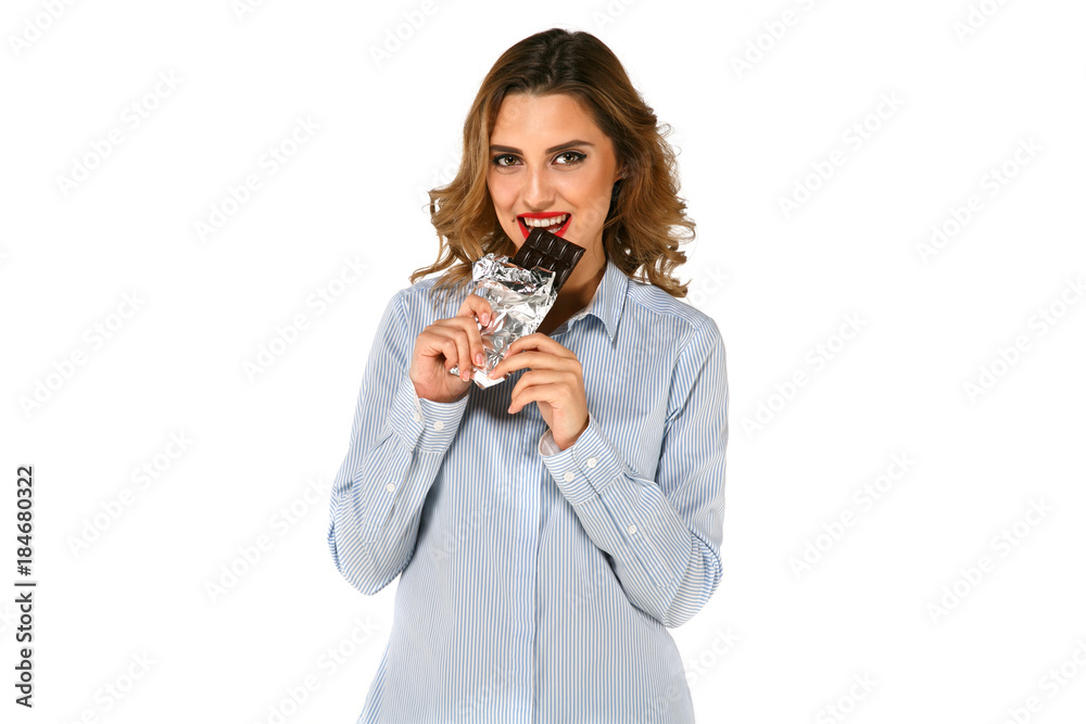Young cute woman biting chocolate wrapped in foil, with red lipstick, over white background. Young cute woman biting chocolate wrapped in foil, with red lipstick, over white background.