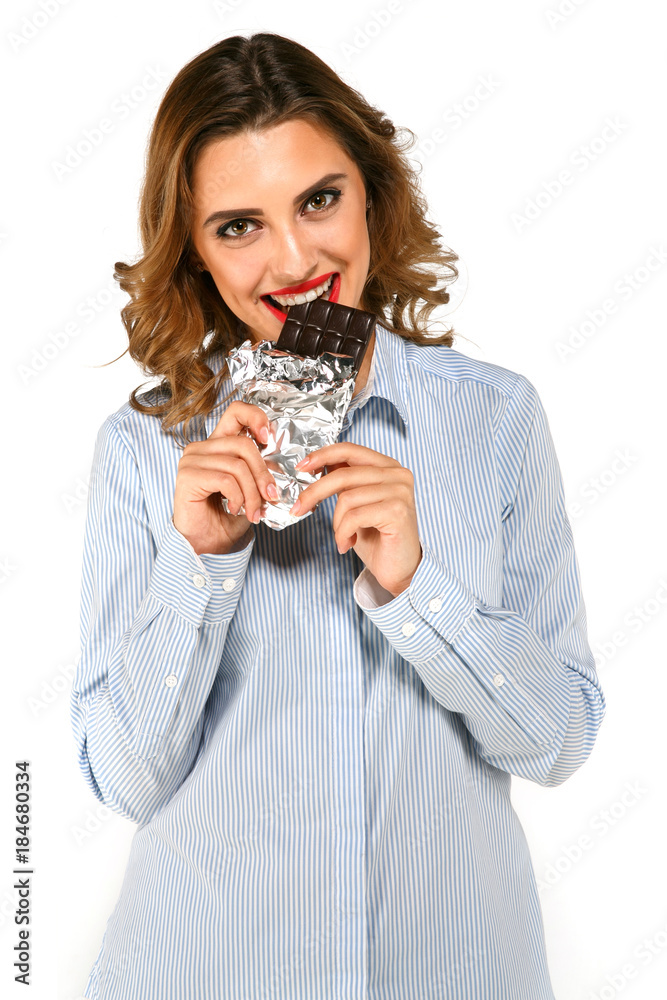 Young beautiful happy woman holding dark chocolate, eating, looking at camera, smiling, with red lips and white teeth, on white background. Young beautiful happy woman holding dark chocolate, eating, looking at camera, smiling, with red lips and white teeth, on white background.
