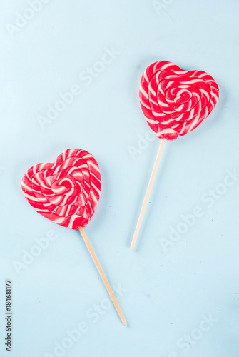 Valentine's day light blue background, greeting card concept, Two red heart lollipops or sweet candy on sticks, top view copy space