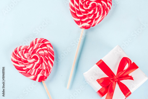 Valentine s day light blue background  greeting card concept  Two red heart lollipops or sweet candy on sticks  with gift box  top view copy space