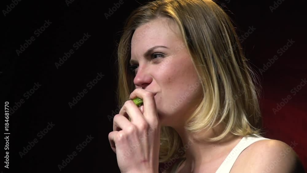 Beautiful woman in a white t-shirt bites a kiwi, slow motion Beautiful woman in a white t-shirt bites a kiwi, slow motion