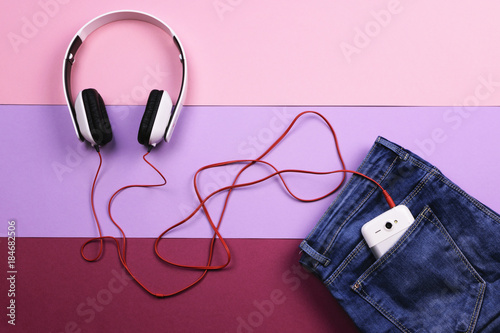 Women's clothing, jeans and headphones on a light violet and lilac background. The view from the top. Flat lay.