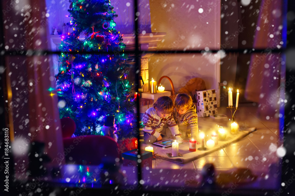 Two little children sitting by a fireplace at home on Christmas Two little children sitting by a fireplace at home on Christmas