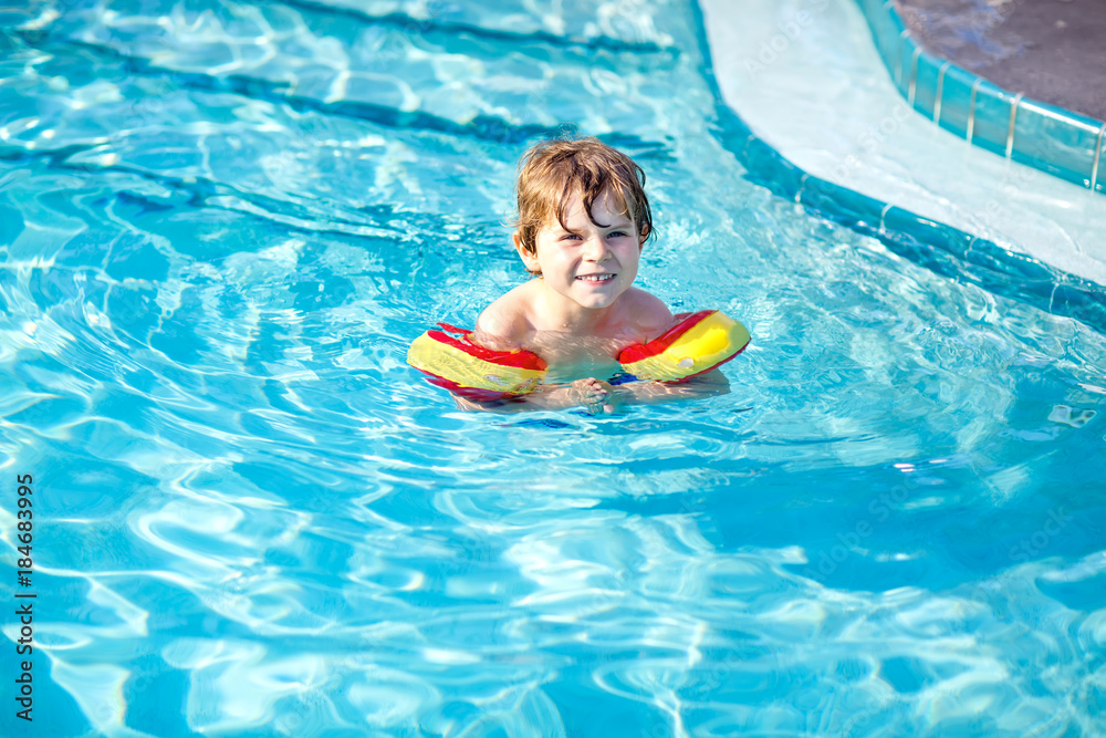 Happy little kid boy having fun in an swimming pool