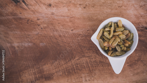 Top view image of raisin in a white cup on wooden background