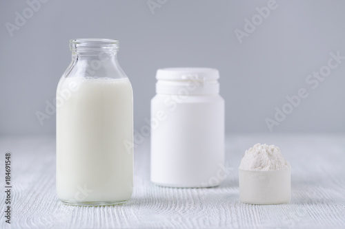 glass bottle of milk and powder on gray background