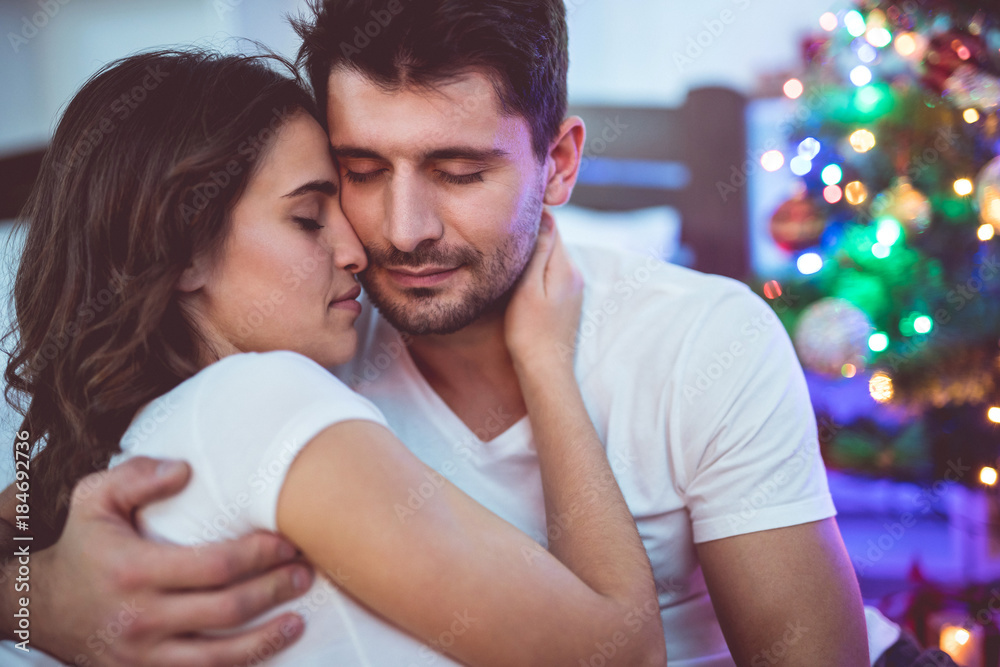 Fototapeta premium The beautiful couple sit near the christmas tree