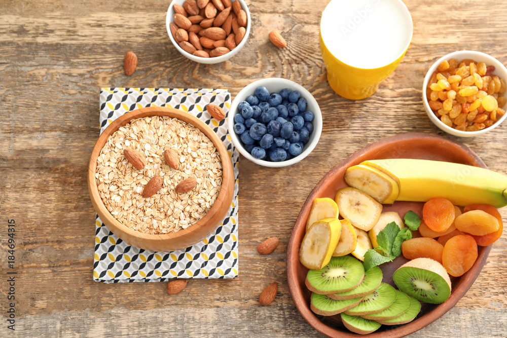 Oatmeal flakes and many different toppings on wooden background