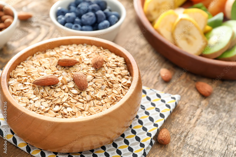 Bowl with oatmeal flakes and almond on wooden background Bowl with oatmeal flakes and almond on wooden background