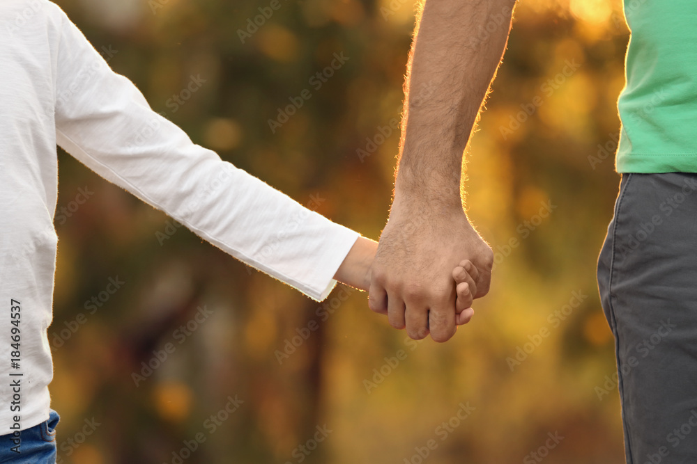 Little boy holding his father's hand outdoors, focus on hands Little boy holding his father's hand outdoors, focus on hands