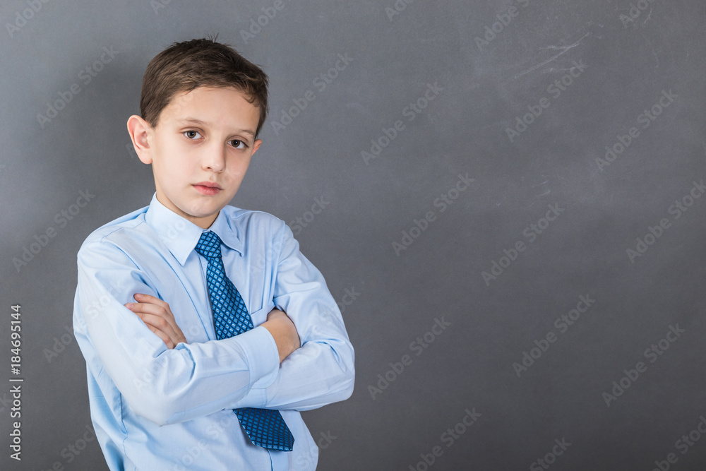 Confident boy student before dark background with copy-space as a blackboard