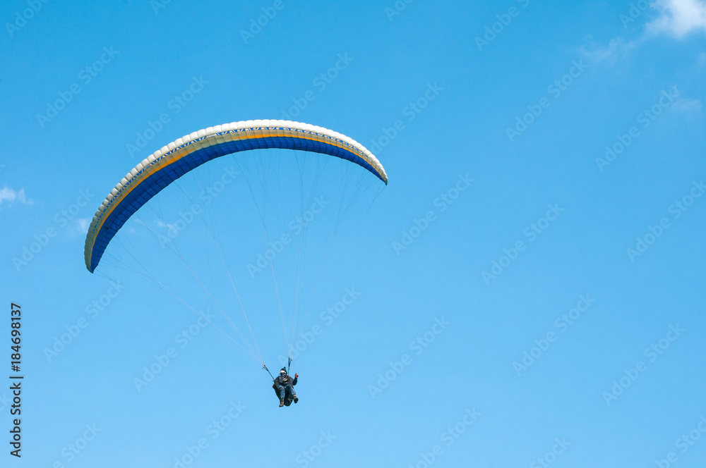 Alone paraglider flying in the blue sky. Paragliding in the sky on a sunny day. Alone paraglider flying in the blue sky. Paragliding in the sky on a sunny day.