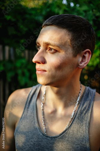 Portrait of a young man in a gray T-shirt in the countryside.