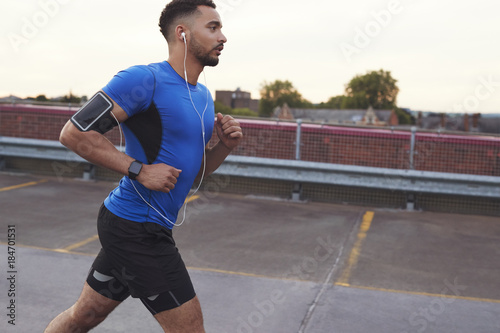Young male athlete running on a road, side view close up © Monkey Business