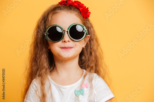 Little cute smiling girl wearing sunglasses looking camera.